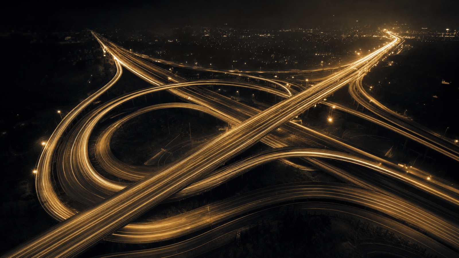 Golden light trails flowing through a highway interchange at night